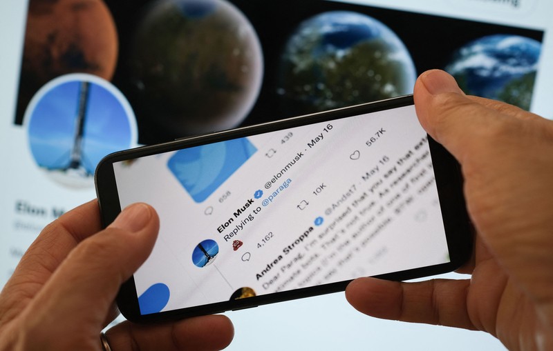 In this illustration photo taken on July 18, 2022 Elon Musk's reply Tweet to Parag Agrawal, the CEO of Twitter, showing a poop emoji is displayed on the screen of a smartphone with Musk Twitter page in the background in Los Angeles. (Photo by Chris DELMAS / AFP) (Photo by CHRIS DELMAS/AFP via Getty Images)