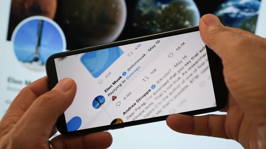 In this illustration photo taken on July 18, 2022 Elon Musk's reply Tweet to Parag Agrawal, the CEO of Twitter, showing a poop emoji is displayed on the screen of a smartphone with Musk Twitter page in the background in Los Angeles. (Photo by Chris DELMAS / AFP) (Photo by CHRIS DELMAS/AFP via Getty Images)