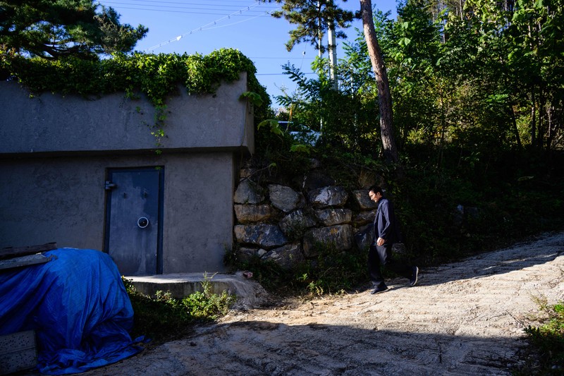 TOPSHOT - This picture taken on October 17, 2022 shows architecture professor Lee Tae-goo opening a hatch door as he prepares to climb out of his bunker, which is buried one metre (three feet) deep and can protect from the radiation fallout of a nuclear blast on his property in Jecheon, some 74 miles (120 km) southeast of the capital Seoul. - If North Korea unleashes a nuclear attack on the South, architecture professor Lee Tae-goo plans to retreat to his purpose-built bunker -- which was funded by a government grant -- and stay underground for at least two weeks to avoid radiation poisoning. - To go with 'SKOREA-NKOREA-NUCLEAR-BUNKER,FOCUS' by Cat Barton and Kang Jin-kyu (Photo by Anthony WALLACE / AFP) / To go with 'SKOREA-NKOREA-NUCLEAR-BUNKER,FOCUS' by Cat Barton and Kang Jin-kyu (Photo by ANTHONY WALLACE/AFP via Getty Images)