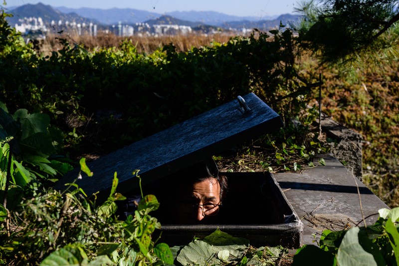 TOPSHOT - This picture taken on October 17, 2022 shows architecture professor Lee Tae-goo opening a hatch door as he prepares to climb out of his bunker, which is buried one metre (three feet) deep and can protect from the radiation fallout of a nuclear blast on his property in Jecheon, some 74 miles (120 km) southeast of the capital Seoul. - If North Korea unleashes a nuclear attack on the South, architecture professor Lee Tae-goo plans to retreat to his purpose-built bunker -- which was funded by a government grant -- and stay underground for at least two weeks to avoid radiation poisoning. - To go with 'SKOREA-NKOREA-NUCLEAR-BUNKER,FOCUS' by Cat Barton and Kang Jin-kyu (Photo by Anthony WALLACE / AFP) / To go with 'SKOREA-NKOREA-NUCLEAR-BUNKER,FOCUS' by Cat Barton and Kang Jin-kyu (Photo by ANTHONY WALLACE/AFP via Getty Images)