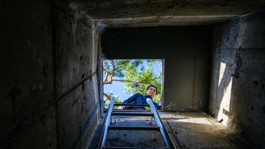 TOPSHOT - This picture taken on October 17, 2022 shows architecture professor Lee Tae-goo opening a hatch door as he prepares to climb out of his bunker, which is buried one metre (three feet) deep and can protect from the radiation fallout of a nuclear blast on his property in Jecheon, some 74 miles (120 km) southeast of the capital Seoul. - If North Korea unleashes a nuclear attack on the South, architecture professor Lee Tae-goo plans to retreat to his purpose-built bunker -- which was funded by a government grant -- and stay underground for at least two weeks to avoid radiation poisoning. - To go with 'SKOREA-NKOREA-NUCLEAR-BUNKER,FOCUS' by Cat Barton and Kang Jin-kyu (Photo by Anthony WALLACE / AFP) / To go with 'SKOREA-NKOREA-NUCLEAR-BUNKER,FOCUS' by Cat Barton and Kang Jin-kyu (Photo by ANTHONY WALLACE/AFP via Getty Images)