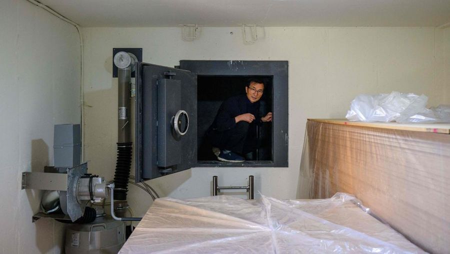 TOPSHOT - This picture taken on October 17, 2022 shows architecture professor Lee Tae-goo opening a hatch door as he prepares to climb out of his bunker, which is buried one metre (three feet) deep and can protect from the radiation fallout of a nuclear blast on his property in Jecheon, some 74 miles (120 km) southeast of the capital Seoul. - If North Korea unleashes a nuclear attack on the South, architecture professor Lee Tae-goo plans to retreat to his purpose-built bunker -- which was funded by a government grant -- and stay underground for at least two weeks to avoid radiation poisoning. - To go with 'SKOREA-NKOREA-NUCLEAR-BUNKER,FOCUS' by Cat Barton and Kang Jin-kyu (Photo by Anthony WALLACE / AFP) / To go with 'SKOREA-NKOREA-NUCLEAR-BUNKER,FOCUS' by Cat Barton and Kang Jin-kyu (Photo by ANTHONY WALLACE/AFP via Getty Images)