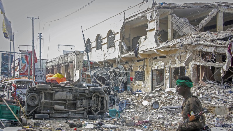 A Somali soldier walks through the scene of a double car-bomb attack in Mogadishu, Somalia, Saturday Oct. 29, 2022. Two car bombs exploded Saturday at a busy junction in Somalia's capital near key government offices, leaving 