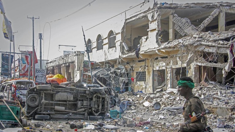A Somali soldier walks through the scene of a double car-bomb attack in Mogadishu, Somalia, Saturday Oct. 29, 2022. Two car bombs exploded Saturday at a busy junction in Somalia's capital near key government offices, leaving 
