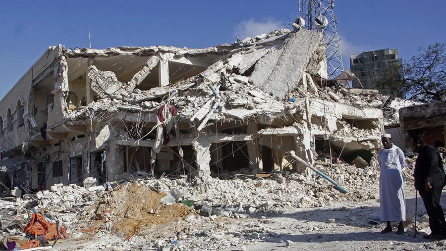 People observe a destroyed building at the scene, a day after a double car bomb attack at a busy junction in Mogadishu, Somalia Sunday, Oct. 30, 2022. Somalia's president says multiple people were killed in Saturday's attacks and the toll could rise in the country's deadliest attack since a truck bombing at the same spot five years ago killed more than 500. (AP Photo/Farah Abdi Warsameh)