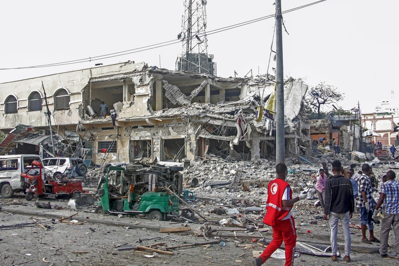 A Somali soldier walks through the scene of a double car-bomb attack in Mogadishu, Somalia, Saturday Oct. 29, 2022. Two car bombs exploded Saturday at a busy junction in Somalia's capital near key government offices, leaving 