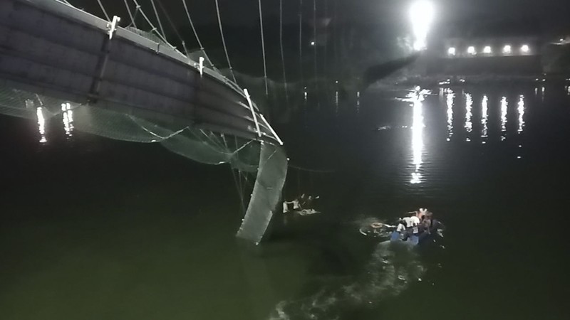 Setidaknya 60 orang tewas setelah satu jembatan gantung di India yang sudah berusia 100 tahun ambruk pada Minggu (30/10). (AP/Rajesh Ambaliya)