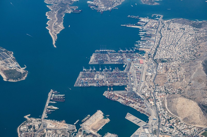 Aerial view from an airplane window of Pireaus port GRPIR. View of large freighter ships, nautical vessels docked while loading - unloading containers and cargo via cranes at the piers of the port at the logistics and container terminal of Perama near the commercial port of Piraeus with thousands of stacked containers. Pireas Port is a logistics hub, the largest Greek port and one of the largest in Europe, serving Athens, Attica and Greece since ancient times. The majority of Port of Piraeus is owned by China COSCO Shipping, the third largest container ship company in the world. As of 2021 the total capacity is at 8,3m TEUs. Piraeus, Greece on August 7, 2022 (Nicolas Economou/NurPhoto via Getty Images)