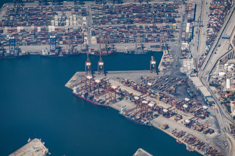 Aerial view from an airplane window of Pireaus port GRPIR. View of large freighter ships, nautical vessels docked while loading - unloading containers and cargo via cranes at the piers of the port at the logistics and container terminal of Perama near the commercial port of Piraeus with thousands of stacked containers. Pireas Port is a logistics hub, the largest Greek port and one of the largest in Europe, serving Athens, Attica and Greece since ancient times. The majority of Port of Piraeus is owned by China COSCO Shipping, the third largest container ship company in the world. As of 2021 the total capacity is at 8,3m TEUs. Piraeus, Greece on August 7, 2022 (Nicolas Economou/NurPhoto via Getty Images) Aerial view from an airplane window of Pireaus port GRPIR. View of large freighter ships, nautical vessels docked while loading - unloading containers and cargo via cranes at the piers of the port at the logistics and container terminal of Perama near the commercial port of Piraeus with thousands of stacked containers. Pireas Port is a logistics hub, the largest Greek port and one of the largest in Europe, serving Athens, Attica and Greece since ancient times. The majority of Port of Piraeus is owned by China COSCO Shipping, the third largest container ship company in the world. As of 2021 the total capacity is at 8,3m TEUs. Piraeus, Greece on August 7, 2022 (Nicolas Economou/NurPhoto via Getty Images)