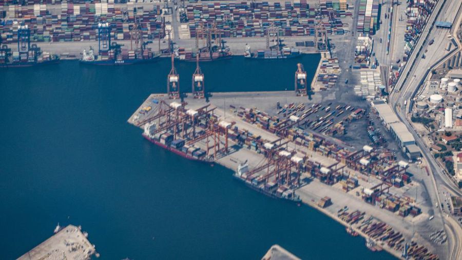 Aerial view from an airplane window of Pireaus port GRPIR. View of large freighter ships, nautical vessels docked while loading - unloading containers and cargo via cranes at the piers of the port at the logistics and container terminal of Perama near the commercial port of Piraeus with thousands of stacked containers. Pireas Port is a logistics hub, the largest Greek port and one of the largest in Europe, serving Athens, Attica and Greece since ancient times. The majority of Port of Piraeus is owned by China COSCO Shipping, the third largest container ship company in the world. As of 2021 the total capacity is at 8,3m TEUs. Piraeus, Greece on August 7, 2022 (Nicolas Economou/NurPhoto via Getty Images)