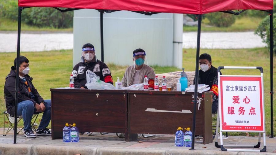 ZHENGZHOU, CHINA - OCTOBER 30: Staff members work at a service point to provide water and food for Foxconn employees before their departure on October 30, 2022 in Zhengzhou, Henan Province of China. Shuttle buses have been arranged by local authorities to facilitate the return trips of Foxconn factory workers to their hometowns after COVID-19 infections were reported in the city Zhengzhou. (VCG/VCG via Getty Images)