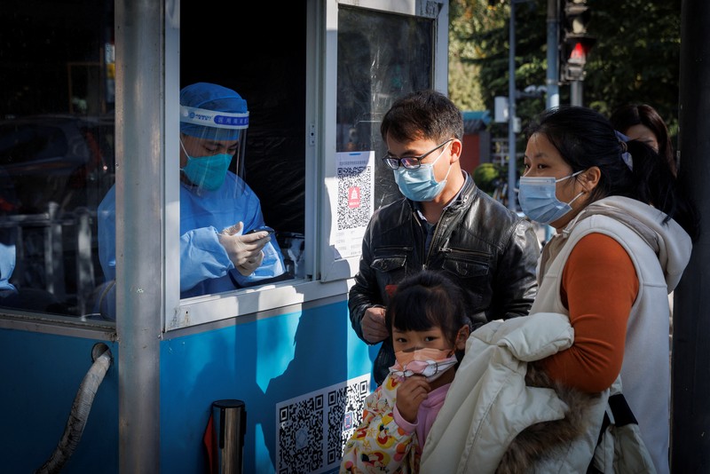 A woman gets her routine COVID-19 throat swab at a coronavirus testing site setup along a pedestrian walkway in Beijing, Thursday, Nov. 3, 2022. The ruling Communist Party is enforcing a 