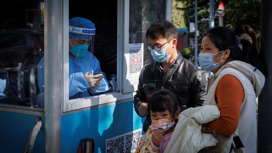 A woman gets her routine COVID-19 throat swab at a coronavirus testing site setup along a pedestrian walkway in Beijing, Thursday, Nov. 3, 2022. The ruling Communist Party is enforcing a 