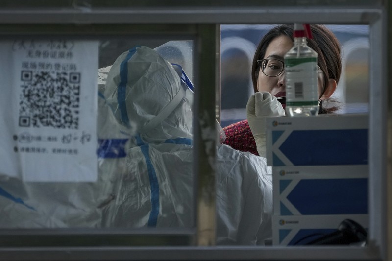 Virus Outbreak China A woman gets her routine COVID-19 throat swab at a coronavirus testing site setup along a pedestrian walkway in Beijing, Thursday, Nov. 3, 2022. The ruling Communist Party is enforcing a
