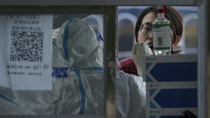 A woman gets her routine COVID-19 throat swab at a coronavirus testing site setup along a pedestrian walkway in Beijing, Thursday, Nov. 3, 2022. The ruling Communist Party is enforcing a 