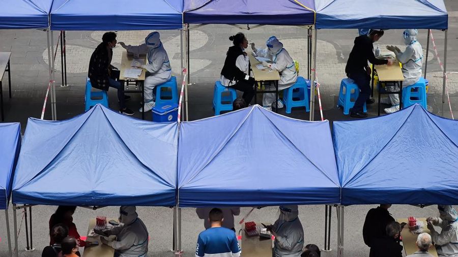 A woman gets her routine COVID-19 throat swab at a coronavirus testing site setup along a pedestrian walkway in Beijing, Thursday, Nov. 3, 2022. The ruling Communist Party is enforcing a 