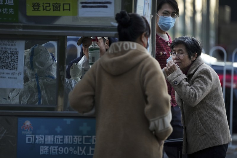 Virus Outbreak China A woman gets her routine COVID-19 throat swab at a coronavirus testing site setup along a pedestrian walkway in Beijing, Thursday, Nov. 3, 2022. The ruling Communist Party is enforcing a