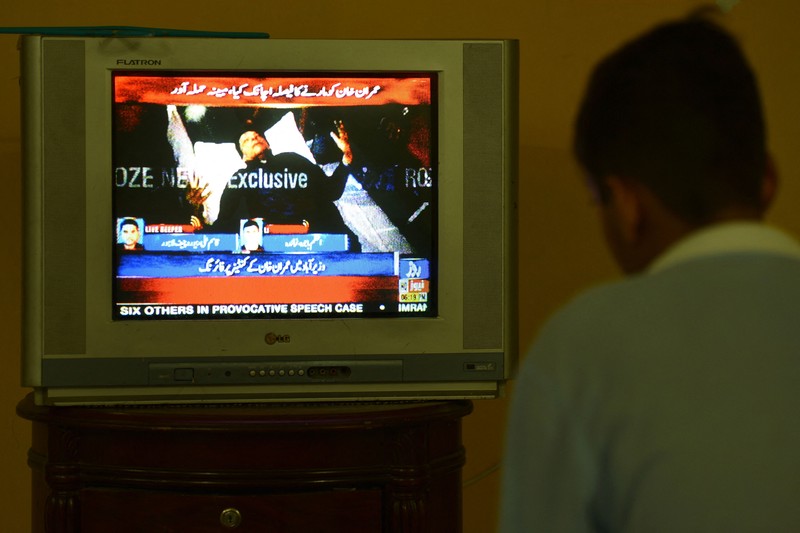 Seorang anak laki-laki menonton saluran televisi yang menayangkan berita tentang mantan perdana menteri Pakistan Imran Khan, di Islamabad pada 3 November 2022. (AFP via Getty Images/FAROOQ NAEEM)