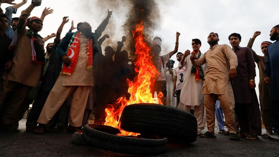 Orang-orang meneriakkan slogan-slogan saat mereka membakar ban untuk memblokir jalan raya utama selama protes mengutuk insiden penembakan pada long march yang diadakan oleh mantan Perdana Menteri Pakistan Imran Khan, di Wazirabad, Pakistan 4 November 2022. (REUTERS/AKHTAR SOOMRO)