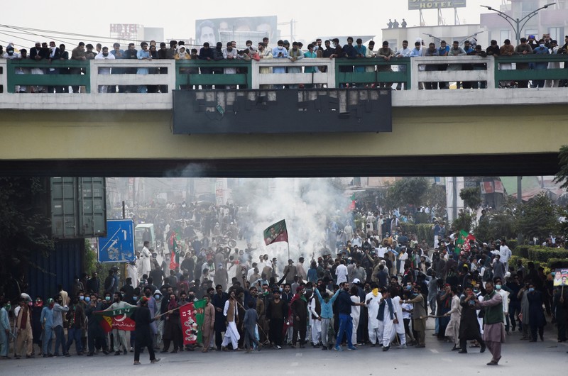 Seorang petugas polisi menembakkan gas air mata untuk membubarkan orang-orang selama protes mengutuk insiden penembakan pada long march yang diadakan oleh mantan Perdana Menteri Pakistan Imran Khan di Wazirabad, di Rawalpindi, Pakistan 4 November 2022. (REUTERS/STRINGER)