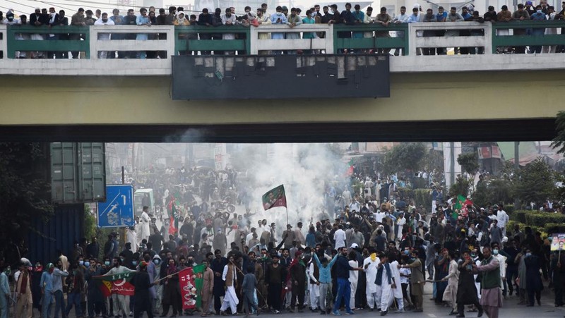 Seorang petugas polisi menembakkan gas air mata untuk membubarkan orang-orang selama protes mengutuk insiden penembakan pada long march yang diadakan oleh mantan Perdana Menteri Pakistan Imran Khan di Wazirabad, di Rawalpindi, Pakistan 4 November 2022. (REUTERS/STRINGER)