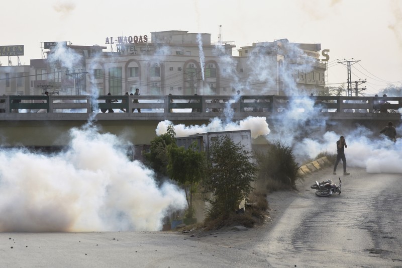 Seorang petugas polisi menembakkan gas air mata untuk membubarkan orang-orang selama protes mengutuk insiden penembakan pada long march yang diadakan oleh mantan Perdana Menteri Pakistan Imran Khan di Wazirabad, di Rawalpindi, Pakistan 4 November 2022. (REUTERS/STRINGER)