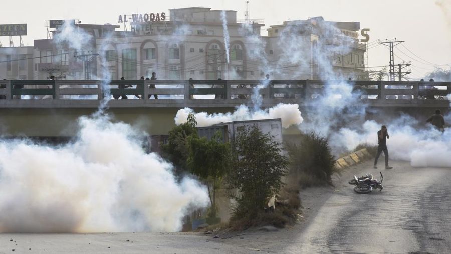 Seorang petugas polisi menembakkan gas air mata untuk membubarkan orang-orang selama protes mengutuk insiden penembakan pada long march yang diadakan oleh mantan Perdana Menteri Pakistan Imran Khan di Wazirabad, di Rawalpindi, Pakistan 4 November 2022. (REUTERS/STRINGER)
