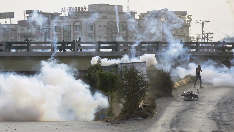 Seorang petugas polisi menembakkan gas air mata untuk membubarkan orang-orang selama protes mengutuk insiden penembakan pada long march yang diadakan oleh mantan Perdana Menteri Pakistan Imran Khan di Wazirabad, di Rawalpindi, Pakistan 4 November 2022. (REUTERS/STRINGER)