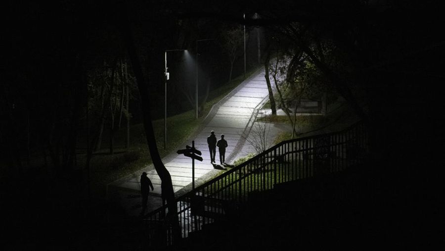 People walk in a park during a blackout in Kyiv, Ukraine, Sunday, Nov. 6, 2022. (AP Photo/Andrew Kravchenko)