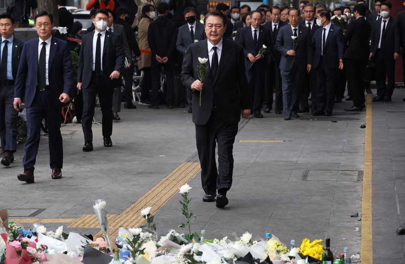 Presiden Korea Selatan Yoon Suk-yeol memegang bunga untuk ditempatkan sebagai penghormatan kepada para korban saat ia mengunjungi lokasi kejadian peristiwa Itaewon saat perayaan Halloween, di Seoul, Korea Selatan, 1 November 2022. (REUTERS/Kim Hong-Ji)