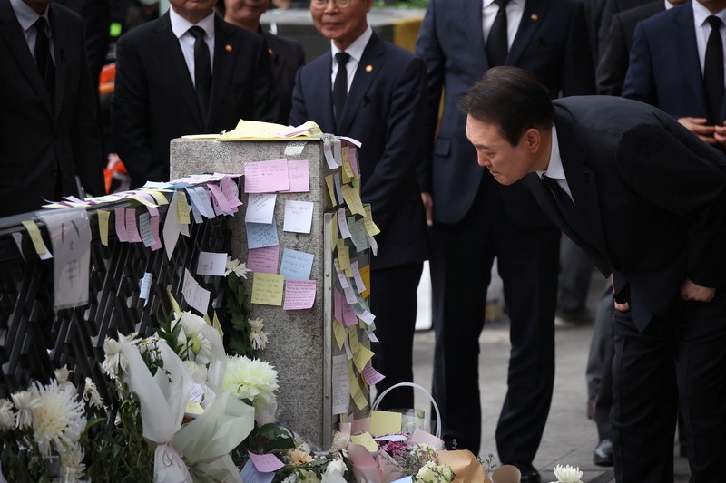 Presiden Korea Selatan Yoon Suk-yeol memegang bunga untuk ditempatkan sebagai penghormatan kepada para korban saat ia mengunjungi lokasi kejadian peristiwa Itaewon saat perayaan Halloween, di Seoul, Korea Selatan, 1 November 2022. (REUTERS/Kim Hong-Ji)