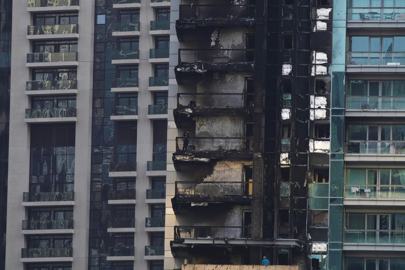 8 Boulevard Walk bertingkat tinggi, kanan bawah, menunjukkan kerusakan akibat kebakaran dengan Burj Khalifa, gedung tertinggi di dunia, terlihat di belakangnya di Dubai, Uni Emirat Arab, Senin, 7 November 2022. The high-rise 8 Boulevard Walk, bottom right, shows fire damage with the Burj Khalifa, the world's tallest building, seen behind it in Dubai, United Arab Emirates, Monday, Nov. 7, 2022. A fire broke out early Monday morning at a 35-story high-rise building in Dubai near the Burj Khalifa, the world's tallest building. (AP Photo/Jon Gambrell)