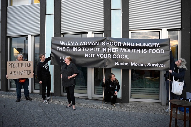 Seorang anggota kelompok aktivis feminis Femen demo Tentang Prostitusi di Jerman Seorang anggota kelompok aktivis feminis Femen mementaskan pertunjukan di samping seorang demonstran yang memegang poster bertuliskan 'Hapus Prostitusi' di depan gedung BPK (Bundespressekonferenz) sebelum konferensi pers yang mempresentasikan hasil penelitian tentang prostitusi dan klien mereka di Berlin, Jerman, Selasa (8/11/2022). (Photo by TOBIAS SCHWARZ/AFP via Getty Images)