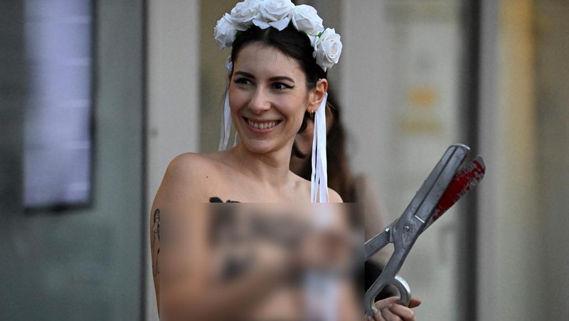 Seorang anggota kelompok aktivis feminis Femen mementaskan pertunjukan di samping seorang demonstran yang memegang poster bertuliskan 'Hapus Prostitusi' di depan gedung BPK (Bundespressekonferenz)  sebelum konferensi pers yang mempresentasikan hasil penelitian tentang prostitusi dan klien mereka di Berlin, Jerman, Selasa (8/11/2022). (Photo by TOBIAS SCHWARZ/AFP via Getty Images)