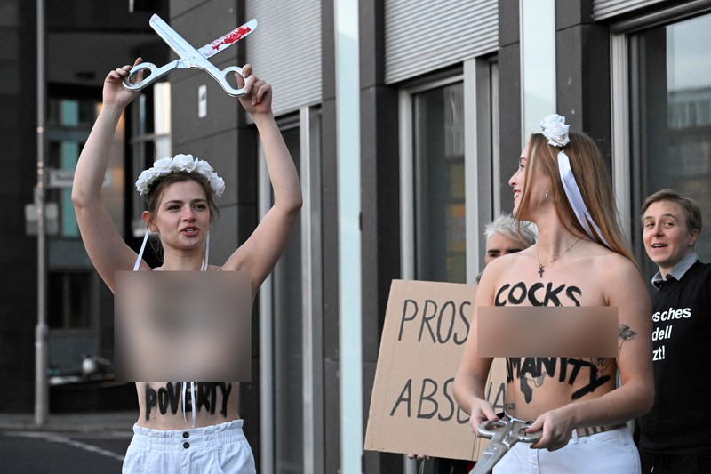 Seorang anggota kelompok aktivis feminis Femen demo Tentang Prostitusi di Jerman Seorang anggota kelompok aktivis feminis Femen mementaskan pertunjukan di samping seorang demonstran yang memegang poster bertuliskan 'Hapus Prostitusi' di depan gedung BPK (Bundespressekonferenz) sebelum konferensi pers yang mempresentasikan hasil penelitian tentang prostitusi dan klien mereka di Berlin, Jerman, Selasa (8/11/2022). (Photo by TOBIAS SCHWARZ/AFP via Getty Images)