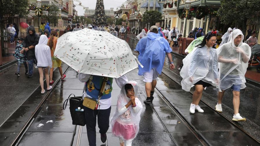 Guests brave the weather in the Magic Kingdom at Walt Disney World in Lake Buena Vista, Fla., Wednesday, Nov. 9, 2022, as conditions deteriorate with the approach of Hurricane Nicole. All 4 Disney parks in Central Florida closed early Wednesday because of the impending storm. (Joe Burbank/Orlando Sentinel via AP)