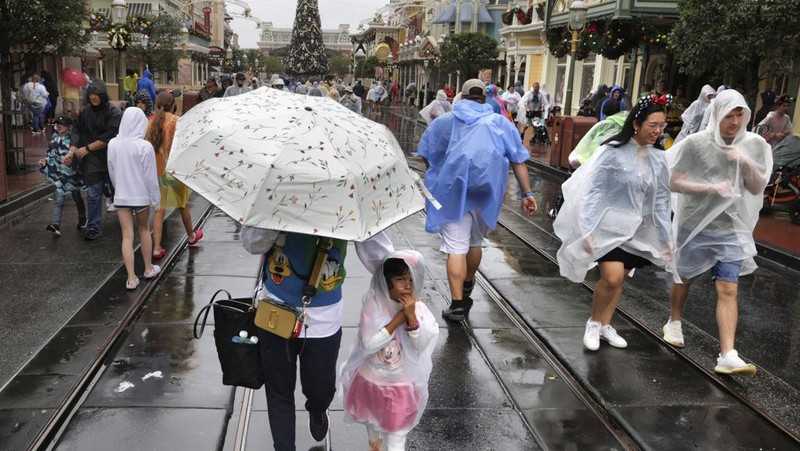 Guests brave the weather in the Magic Kingdom at Walt Disney World in Lake Buena Vista, Fla., Wednesday, Nov. 9, 2022, as conditions deteriorate with the approach of Hurricane Nicole. All 4 Disney parks in Central Florida closed early Wednesday because of the impending storm. (Joe Burbank/Orlando Sentinel via AP)