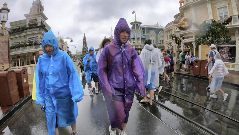 Guests brave the weather in the Magic Kingdom at Walt Disney World in Lake Buena Vista, Fla., Wednesday, Nov. 9, 2022, as conditions deteriorate with the approach of Hurricane Nicole. All 4 Disney parks in Central Florida closed early Wednesday because of the impending storm. (Joe Burbank/Orlando Sentinel via AP)