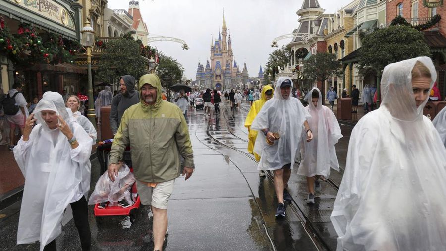 Guests brave the weather in the Magic Kingdom at Walt Disney World in Lake Buena Vista, Fla., Wednesday, Nov. 9, 2022, as conditions deteriorate with the approach of Hurricane Nicole. All 4 Disney parks in Central Florida closed early Wednesday because of the impending storm. (Joe Burbank/Orlando Sentinel via AP)