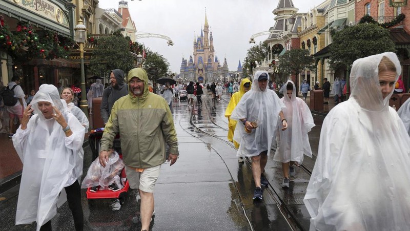 Guests brave the weather in the Magic Kingdom at Walt Disney World in Lake Buena Vista, Fla., Wednesday, Nov. 9, 2022, as conditions deteriorate with the approach of Hurricane Nicole. All 4 Disney parks in Central Florida closed early Wednesday because of the impending storm. (Joe Burbank/Orlando Sentinel via AP)