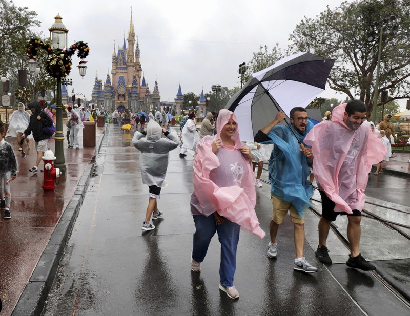 4 taman Disney di Florida Tengah ditutup Rabu pagi karena badai Nicole yang menerjang pantai di Florida, AS, pada (9/11/2022). Guests brave the weather in the Magic Kingdom at Walt Disney World in Lake Buena Vista, Fla., Wednesday, Nov. 9, 2022, as conditions deteriorate with the approach of Hurricane Nicole. All 4 Disney parks in Central Florida closed early Wednesday because of the impending storm. (Joe Burbank/Orlando Sentinel via AP)