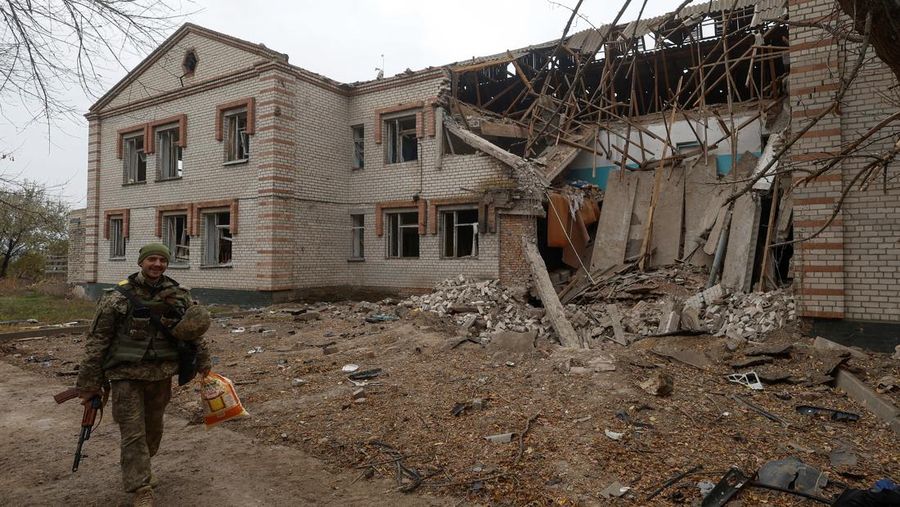 Seorang prajurit Ukraina berjalan melewati gedung taman kanak-kanak yang rusak akibat serangan rudal Rusia di desa Novooleksandrivka, di wilayah Kherson, Ukraina, Rabu (9/11/2022). (REUTERS/Viacheslav Ratynskyi)