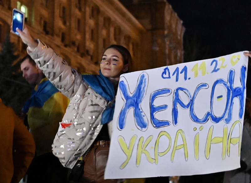 A man holds a Ukranian flag as people gather in Maidan Square to celebrate the liberation of Kherson, in Kyiv on November 11, 2022, amid the Russian invasion of Ukraine. - Ukraine's President Volodymyr Zelensky said on November 11 that Kherson was 