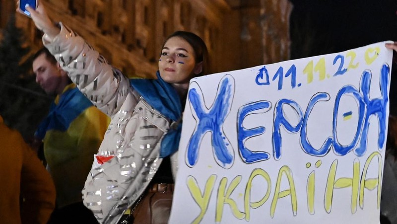 A man holds a Ukranian flag as people gather in Maidan Square to celebrate the liberation of Kherson, in Kyiv on November 11, 2022, amid the Russian invasion of Ukraine. - Ukraine's President Volodymyr Zelensky said on November 11 that Kherson was 