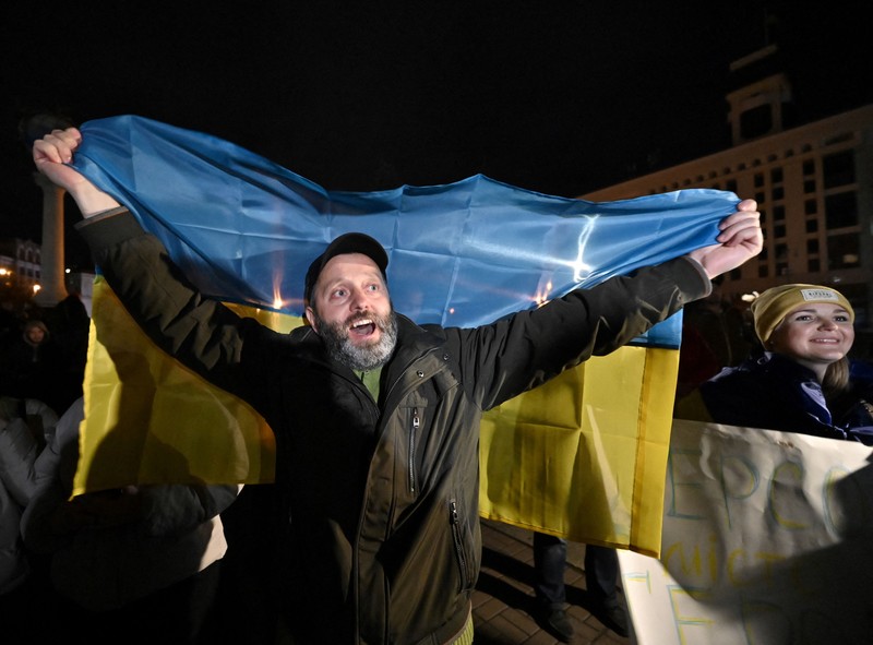 A man holds a Ukranian flag as people gather in Maidan Square to celebrate the liberation of Kherson, in Kyiv on November 11, 2022, amid the Russian invasion of Ukraine. - Ukraine's President Volodymyr Zelensky said on November 11 that Kherson was 