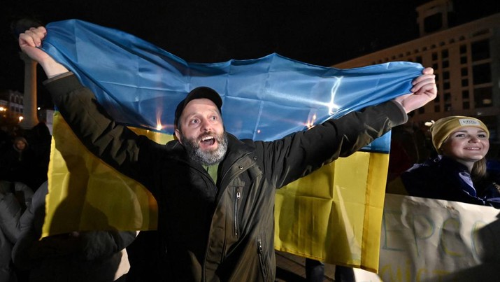A man holds a Ukranian flag as people gather in Maidan Square to celebrate the liberation of Kherson, in Kyiv on November 11, 2022, amid the Russian invasion of Ukraine. - Ukraine's President Volodymyr Zelensky said on November 11 that Kherson was 