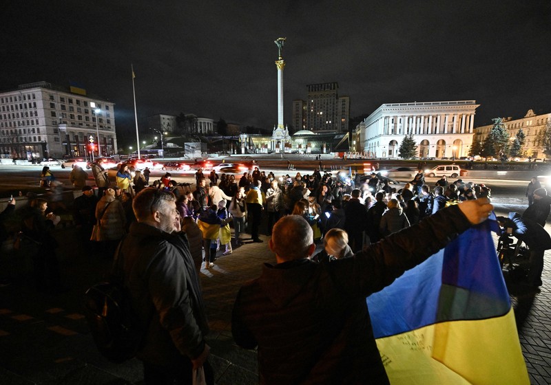 A man holds a Ukranian flag as people gather in Maidan Square to celebrate the liberation of Kherson, in Kyiv on November 11, 2022, amid the Russian invasion of Ukraine. - Ukraine's President Volodymyr Zelensky said on November 11 that Kherson was 