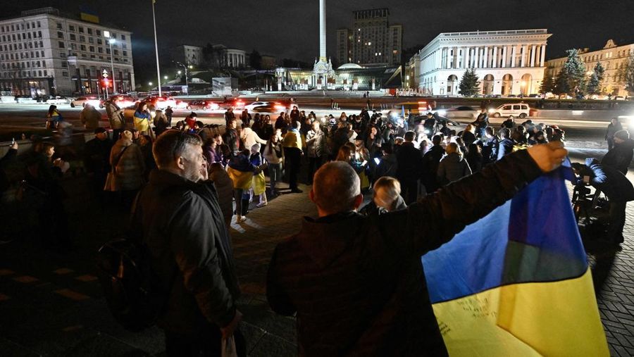 A man holds a Ukranian flag as people gather in Maidan Square to celebrate the liberation of Kherson, in Kyiv on November 11, 2022, amid the Russian invasion of Ukraine. - Ukraine's President Volodymyr Zelensky said on November 11 that Kherson was 