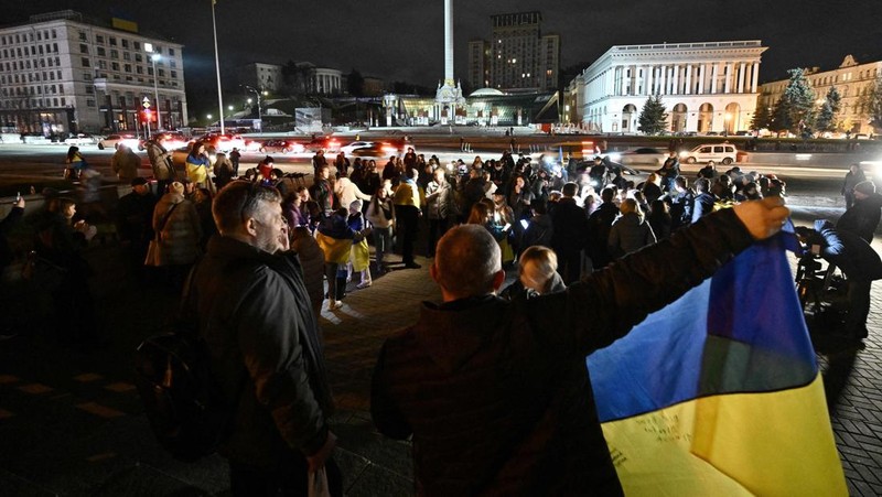 A man holds a Ukranian flag as people gather in Maidan Square to celebrate the liberation of Kherson, in Kyiv on November 11, 2022, amid the Russian invasion of Ukraine. - Ukraine's President Volodymyr Zelensky said on November 11 that Kherson was 
