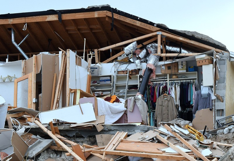 WILBUR-BY-THE-SEA, FLORIDA, UNITED STATES - NOVEMBER 11: A man walks past homes that collapsed onto the beach due to the storm surge and resulting erosion caused by Hurricane Nicole on November 11, 2022 in Wilbur-By-The-Sea, Florida. Nicole made landfall as a Category 1 hurricane before weakening into a tropical storm. (Photo by Paul Hennessy/Anadolu Agency via Getty Images)